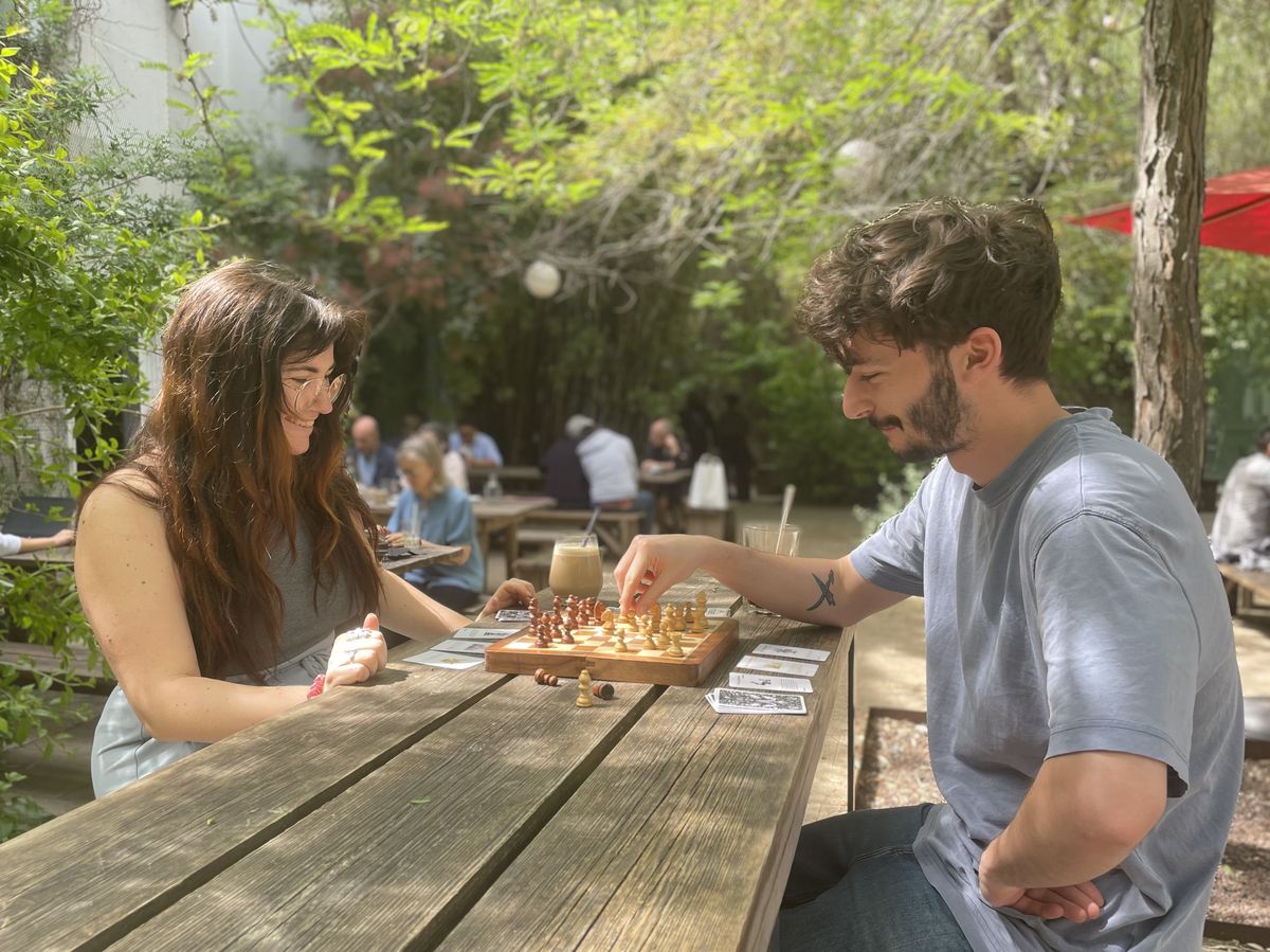 Deux joueurs disputent une partie de Jumble Chess en terrasse